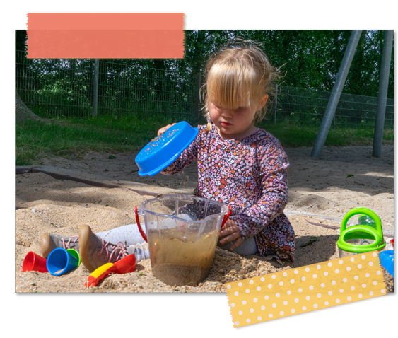 Kleinkind spielt und matscht mit Sieb und Eimer im Sandkasten.
