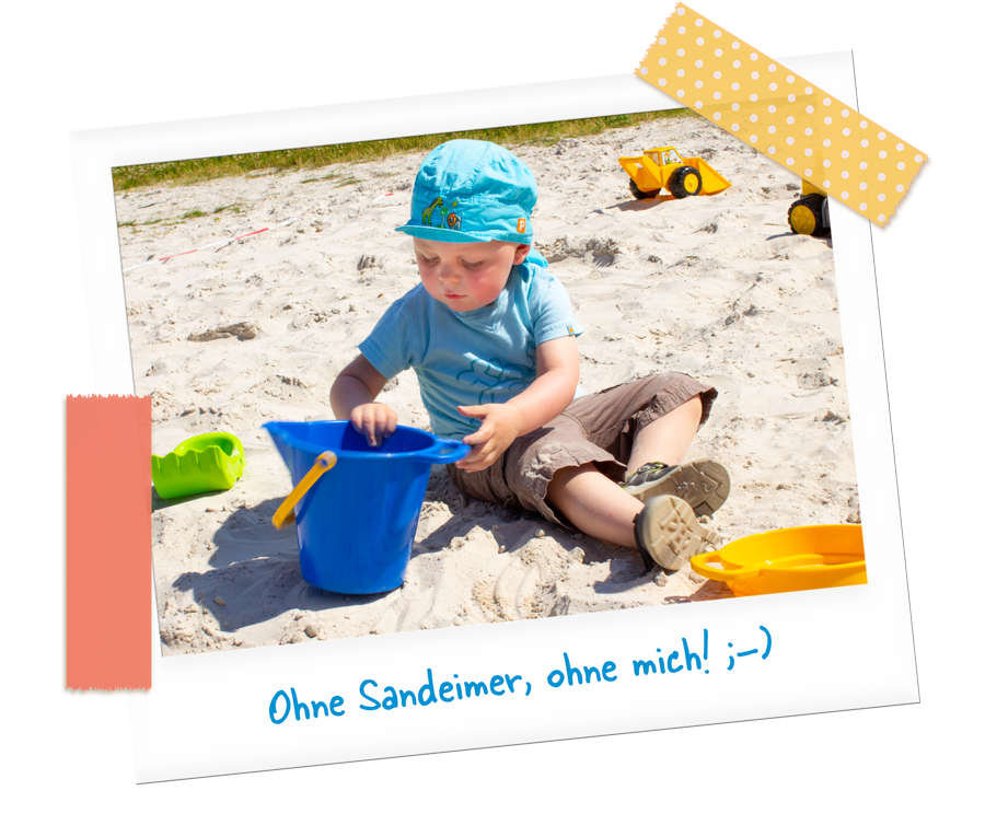 Kleinkind mit blauem Eimer im Sand